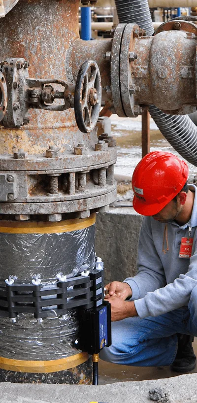 Technician installing a QEQI® unit on a stainless steel pipeline